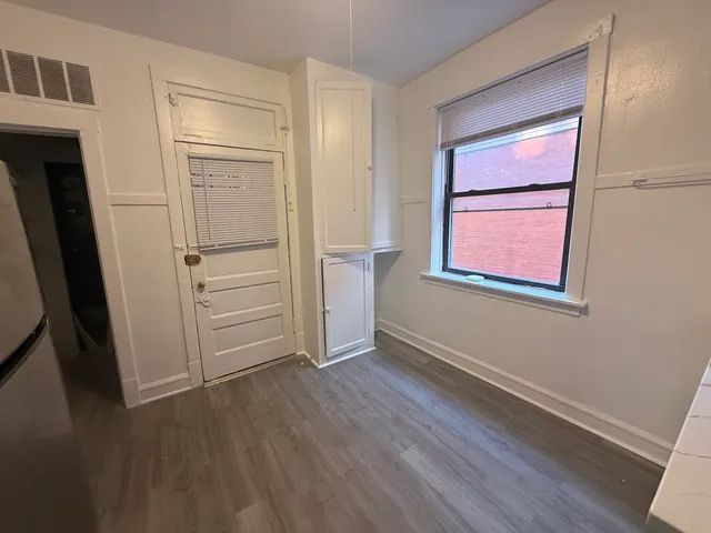 an empty room with wooden floor cabinet and windows