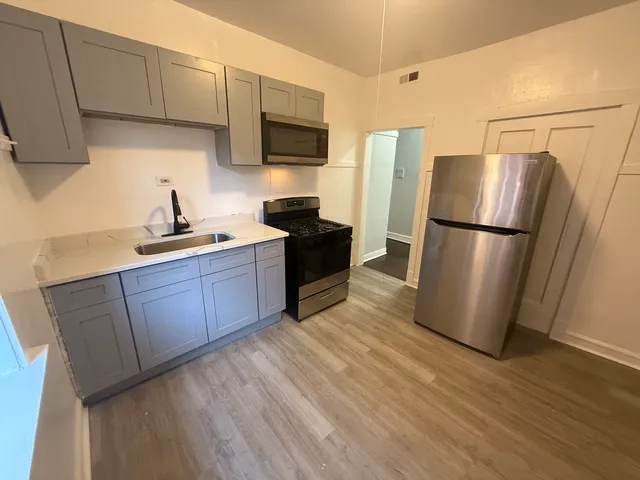 a kitchen with a refrigerator a stove top oven a sink and dishwasher with wooden floor