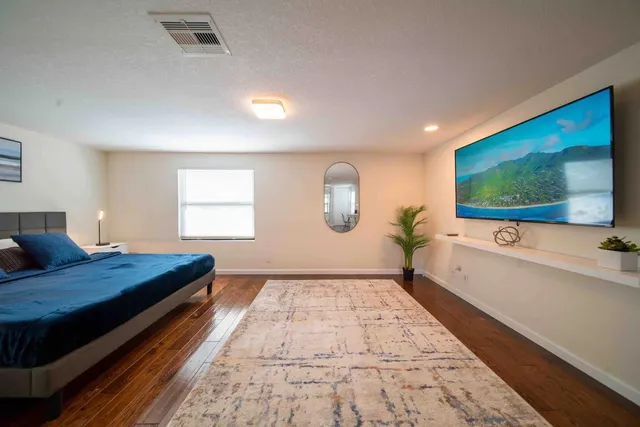 a spacious bedroom with a bed and a flat screen tv