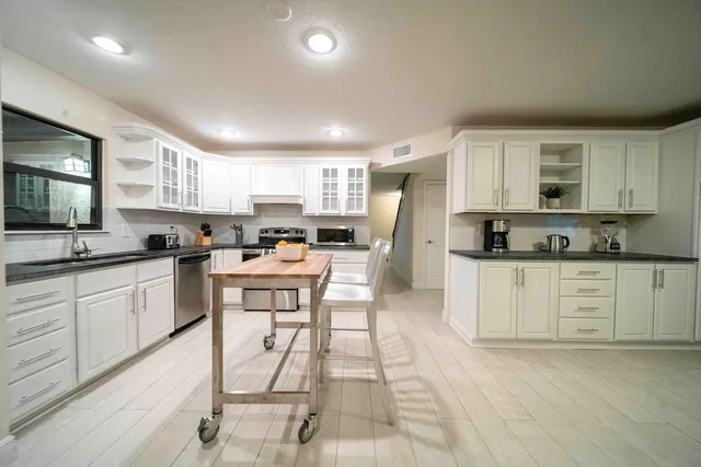 a kitchen with stainless steel appliances kitchen island granite countertop a stove a sink a refrigerator a microwave and cabinets