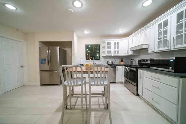 a kitchen with stainless steel appliances granite countertop a stove a sink a refrigerator with a dining table and chairs