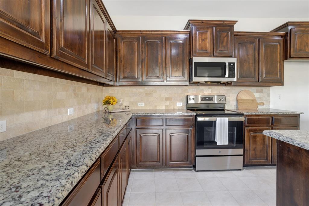 3929 Kennedy Ranch Road Fort Worth, TX 76262 - Photo 7 of 40 Kitchen featuring tasteful backsplash, appliances with stainless steel finishes, dark brown cabinetry, and light tile floors