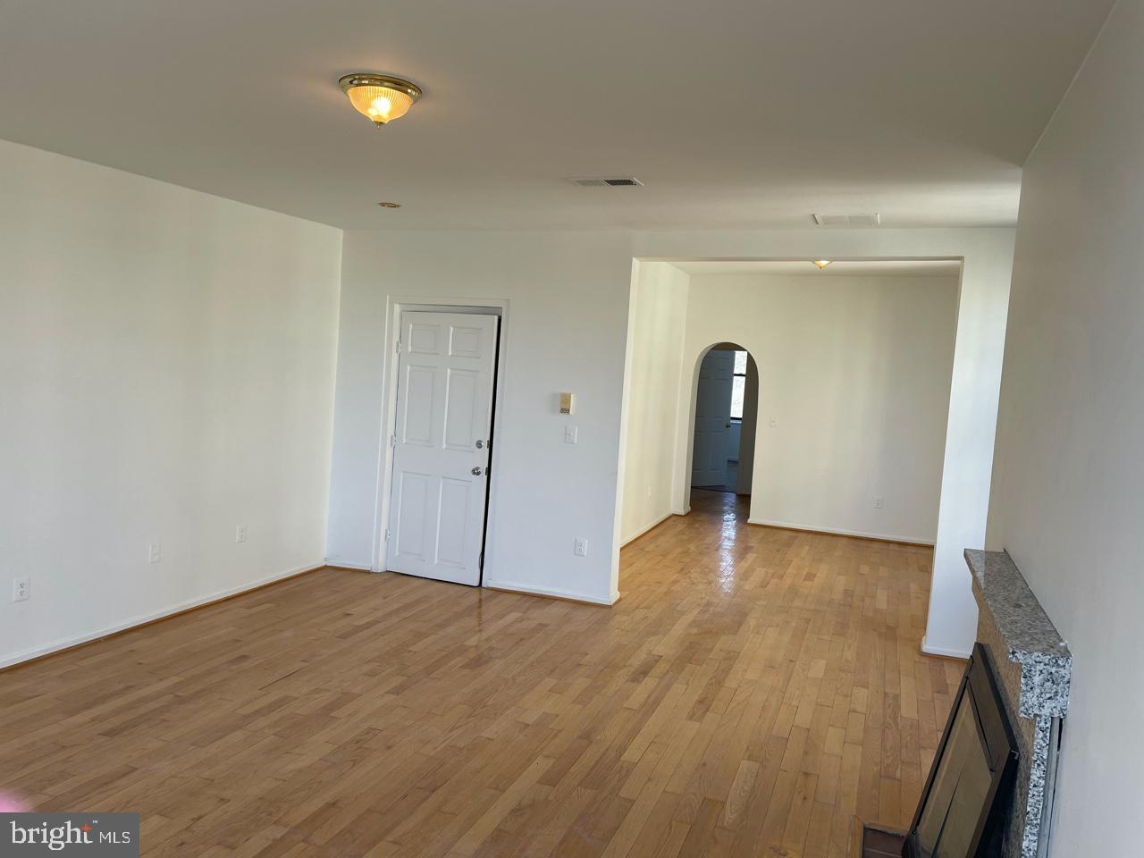 a view of empty room with wooden floor and window