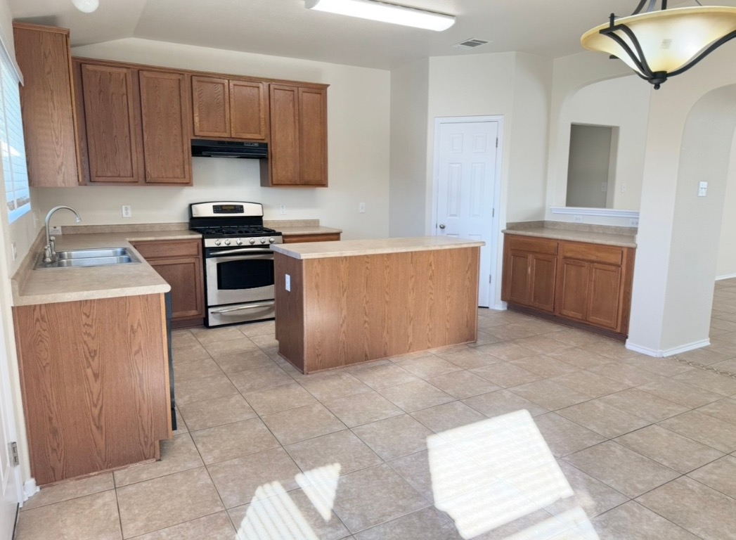 104 Gettysburg Loop Elgin, TX 78621 - Photo 11 of 26 Kitchen with gas range, a center island, light countertops, light tile patterned floors, and lofted ceiling