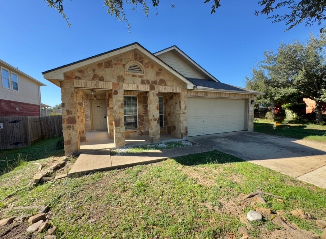 104 Gettysburg Loop Elgin, TX 78621 - Photo 4 of 26 View of front facade with a porch, stone siding, concrete driveway, a garage, and a front lawn