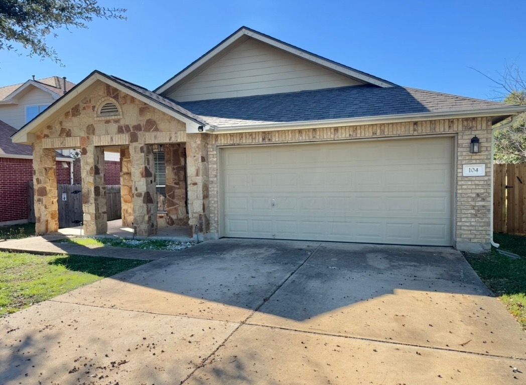 104 Gettysburg Loop Elgin, TX 78621 - Photo 5 of 26 View of front of property with stone siding, roof with shingles, concrete driveway, and an attached garage