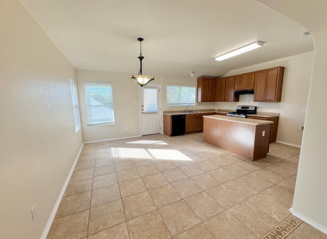 104 Gettysburg Loop Elgin, TX 78621 - Photo 9 of 26 Kitchen featuring a center island, light tile patterned floors, decorative light fixtures, light countertops, and stainless steel gas range
