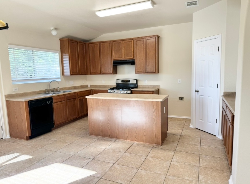 104 Gettysburg Loop Elgin, TX 78621 - Photo 10 of 26 Kitchen with a kitchen island, lofted ceiling, dishwasher, brown cabinetry, and stainless steel gas range oven