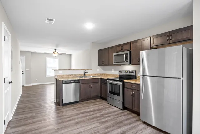 a kitchen with granite countertop a refrigerator stove top oven and sink