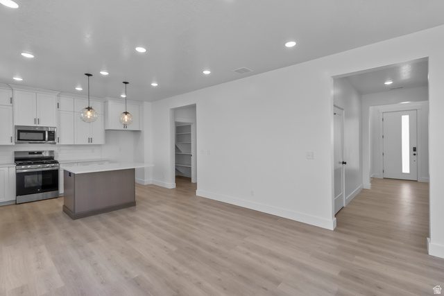 1213 West 500 South Logan, UT 84321 - Photo 4 of 29 Modern kitchen featuring stainless steel appliances, white cabinetry, and a central island with a contrasting base