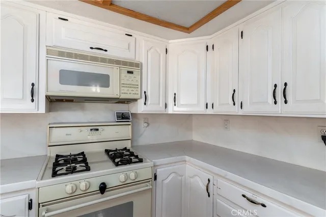 a kitchen with white cabinets and appliances