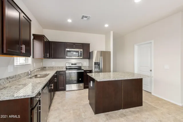 a kitchen with stainless steel appliances granite countertop a refrigerator and wooden cabinets