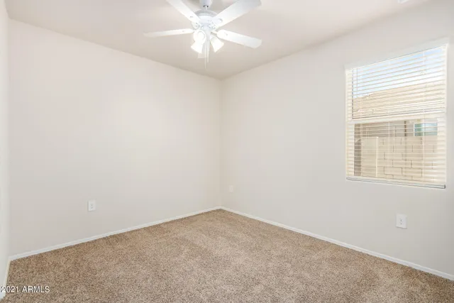 an empty room with a window and a fan