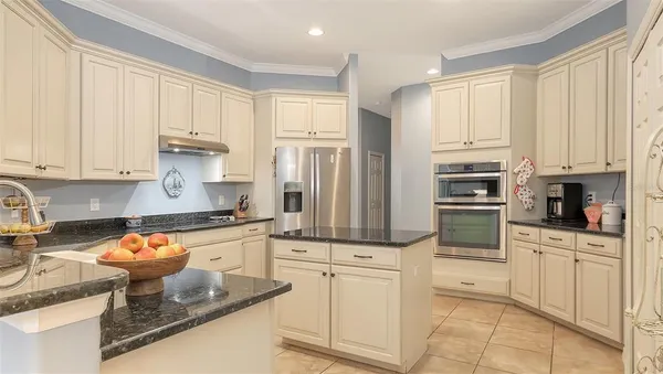 a kitchen with stainless steel appliances granite countertop a refrigerator a stove and white cabinets with wooden floor