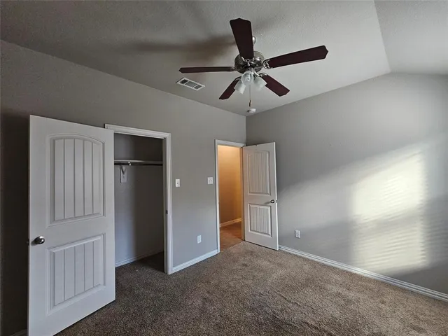 an empty room with a chandelier fan and windows