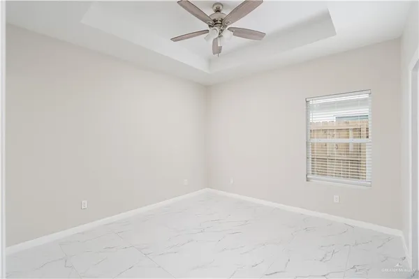 an empty room with a chandelier fan and windows