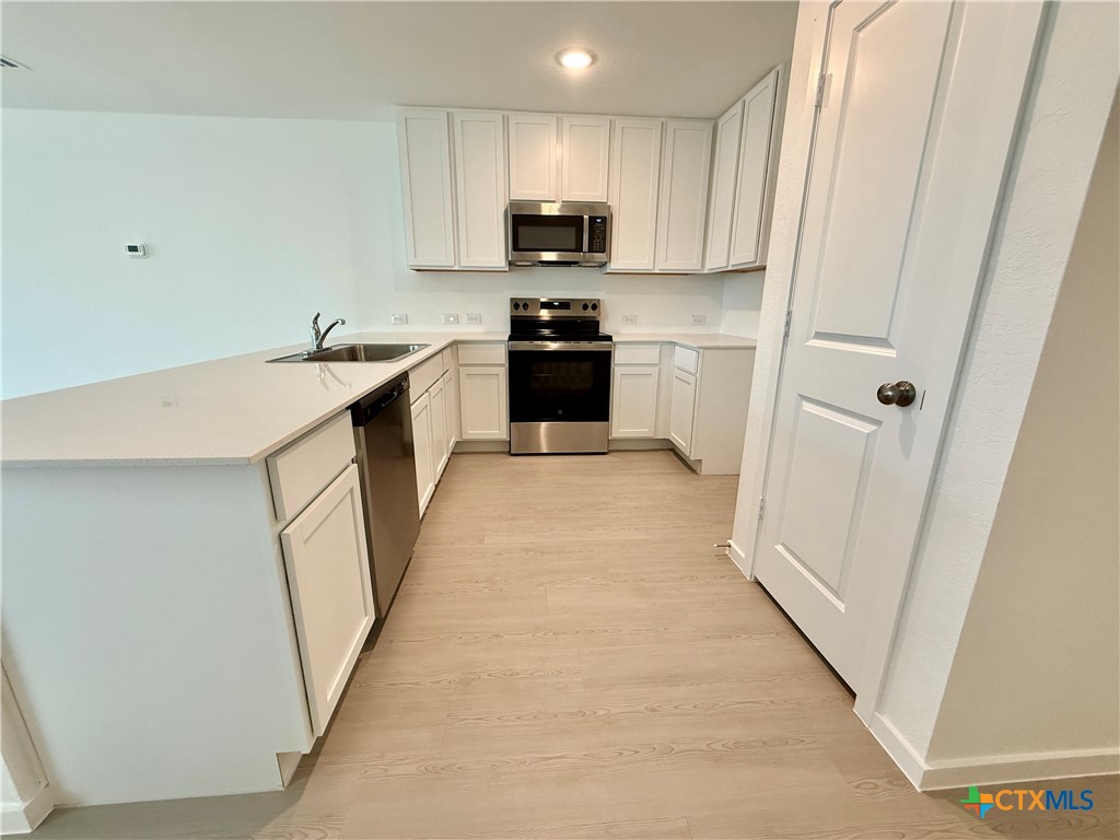 413 Moscato Road New Braunfels, TX 78130 - Photo 8 of 28 a kitchen with granite countertop white cabinets and black appliances