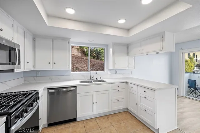 a kitchen with white cabinets appliances a sink and a window