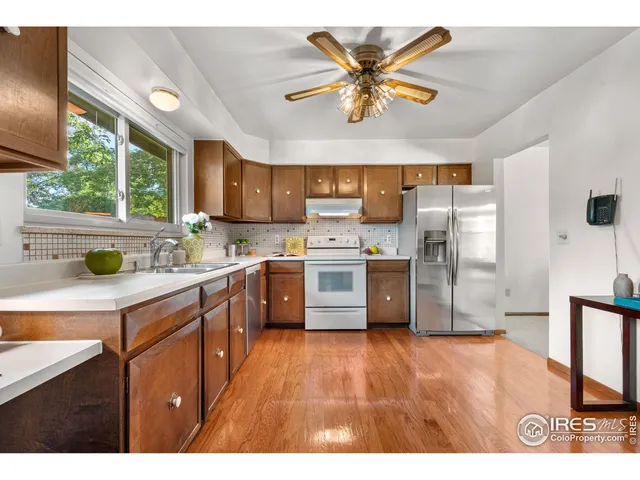 a kitchen with stainless steel appliances a sink a stove a refrigerator cabinets and a large window