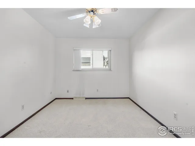 an empty room with a chandelier fan and windows