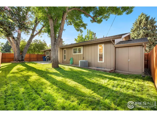 a backyard of a house with plants and large tree