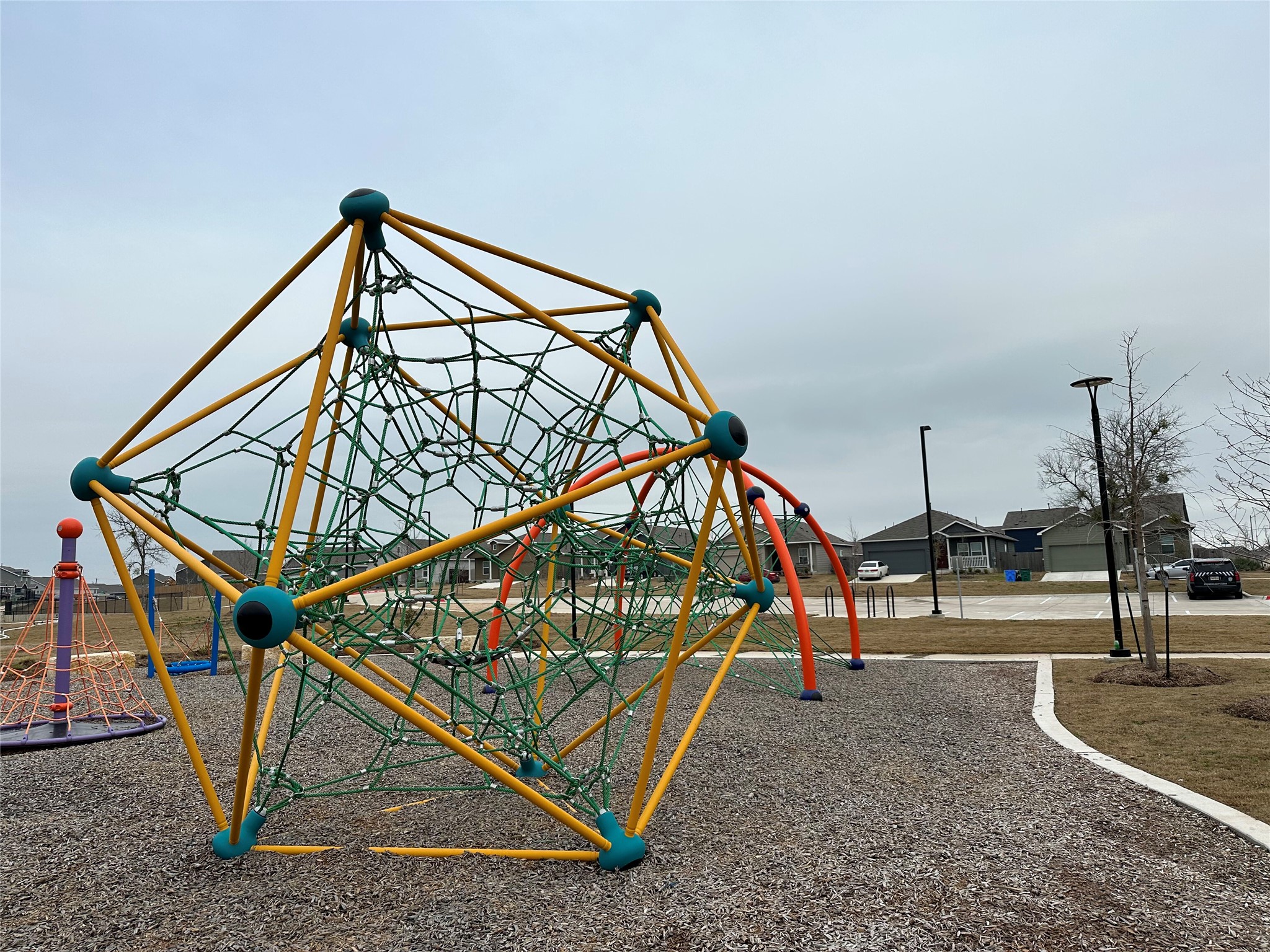 13501 Mussel Run Elgin, TX 78621 - Photo 23 of 28 Recreational park area featuring a geometric climbing structure, a rope climbing dome, and a multi-color archway