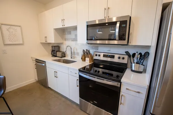 a kitchen with stainless steel appliances a stove a microwave a sink and cabinets