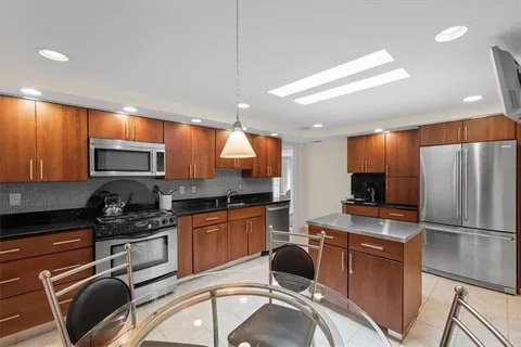 a kitchen with granite countertop stainless steel appliances a refrigerator stove top oven and sink