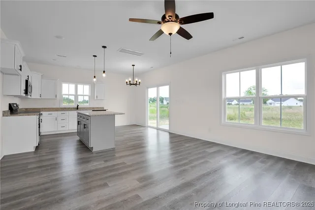 an empty room with wooden floor ceiling fan and windows