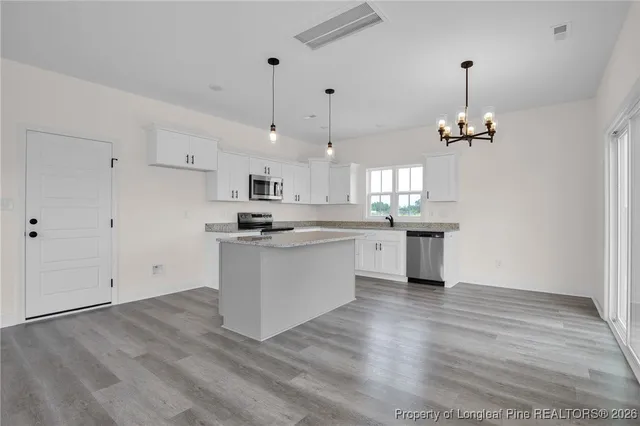 a kitchen with stainless steel appliances granite countertop a sink a stove a refrigerator and white cabinets