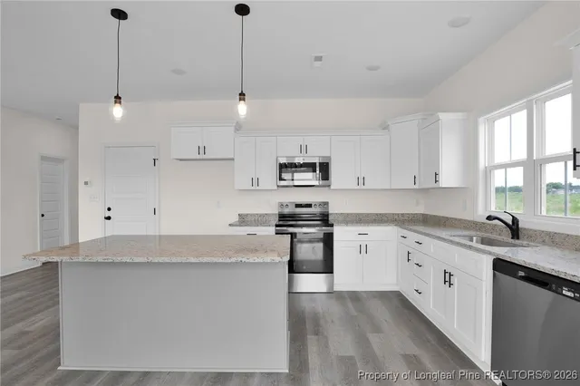 a large kitchen with stainless steel appliances granite countertop a stove oven a sink dishwasher and a refrigerator with wooden floor