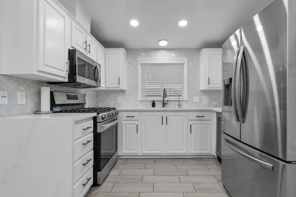 a kitchen with stainless steel appliances granite countertop a refrigerator sink and stove