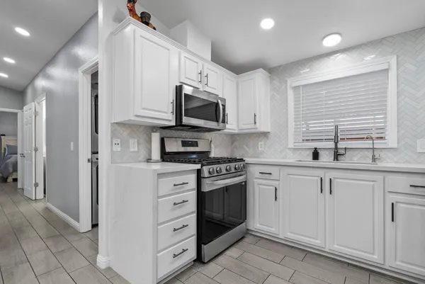 a kitchen with stainless steel appliances granite countertop white cabinets sink and a microwave