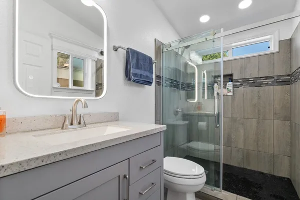 a bathroom with a granite countertop sink toilet and shower