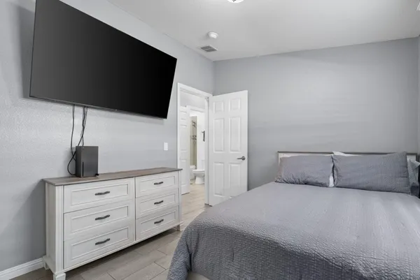 a bedroom with a large bed and a flat tv screen on dresser