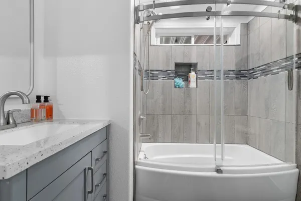 a bathroom with a granite countertop sink and a bathtub with shower