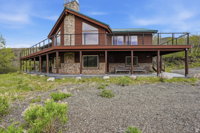 6 Beaver Springs Rancheros Oakley, UT 84055 - Photo 3 of 68 Wood-sided exterior featuring extensive stone accents, a multi-level deck with black railing, large picture windows, and a prominent stone chimney