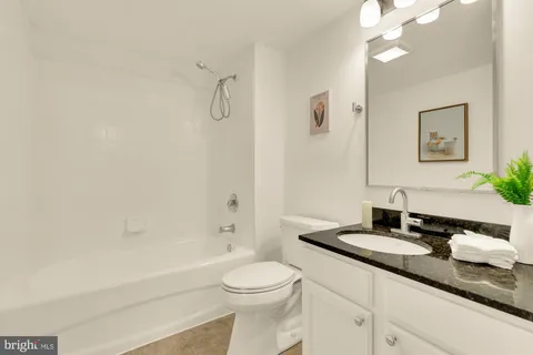 a bathroom with a granite countertop sink a toilet and a mirror