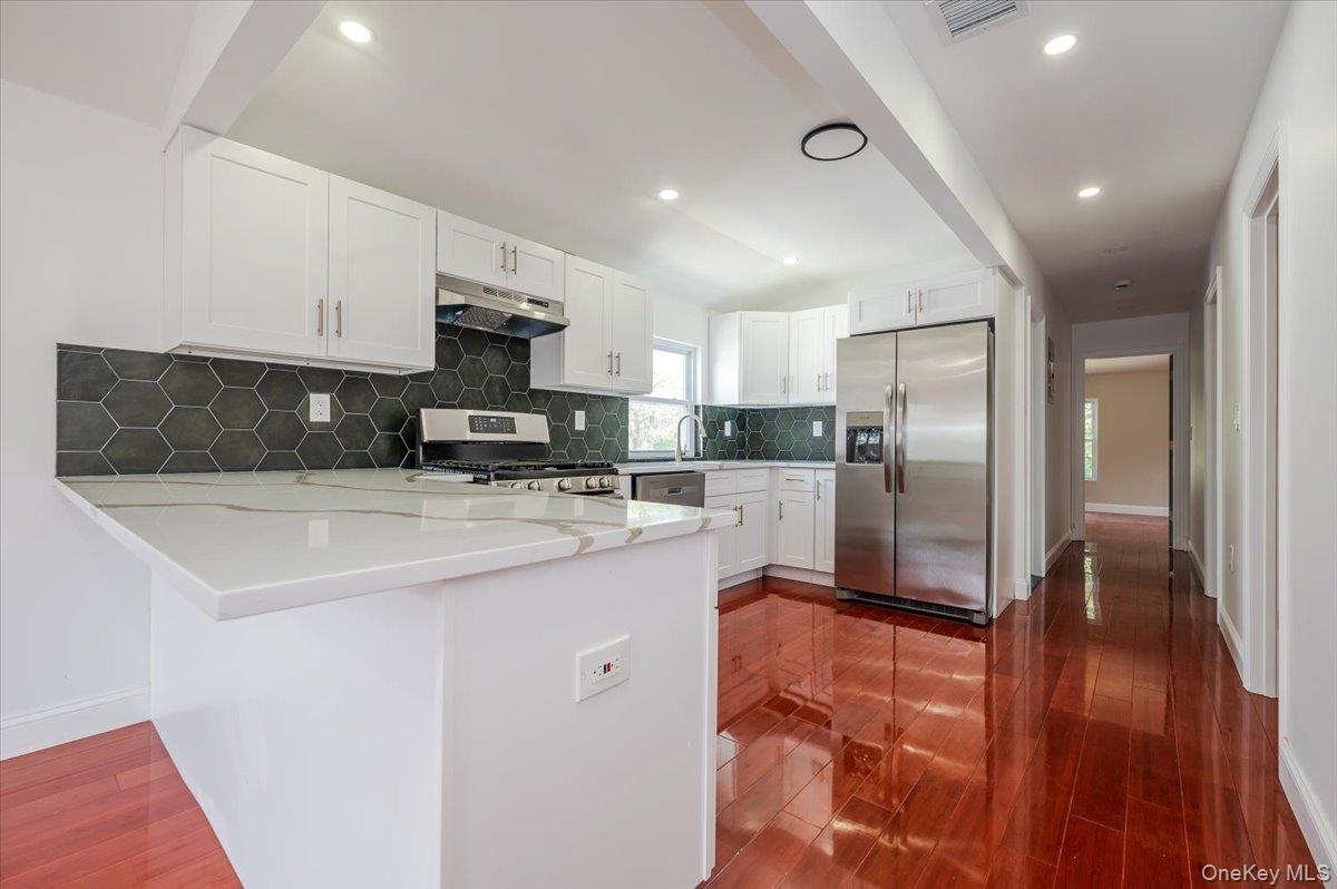 10709 220th Street Queens, NY 11429 - Photo 7 of 14 a kitchen with stainless steel appliances granite countertop a sink a stove a refrigerator and a oven with wooden floor