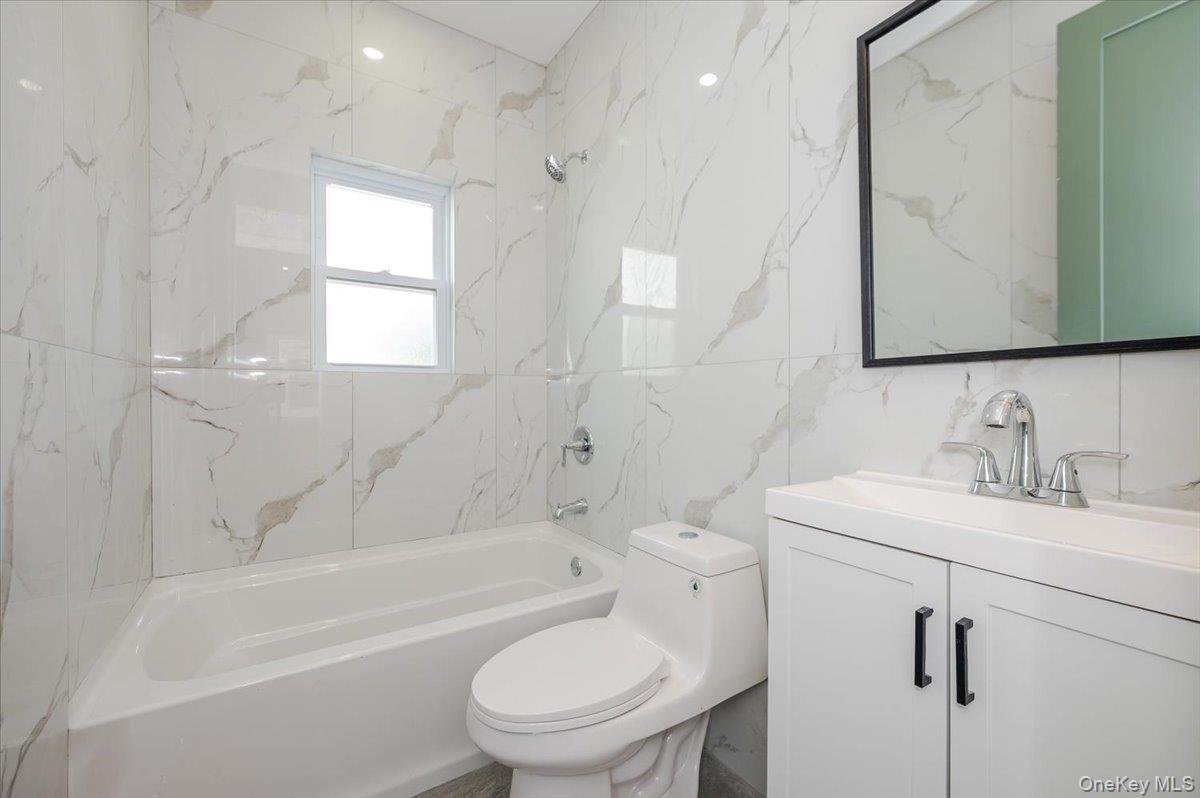 10709 220th Street Queens, NY 11429 - Photo 10 of 14 a bathroom with a granite countertop toilet a sink and a bathtub