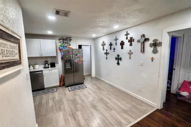 a view of a refrigerator in kitchen and an empty room