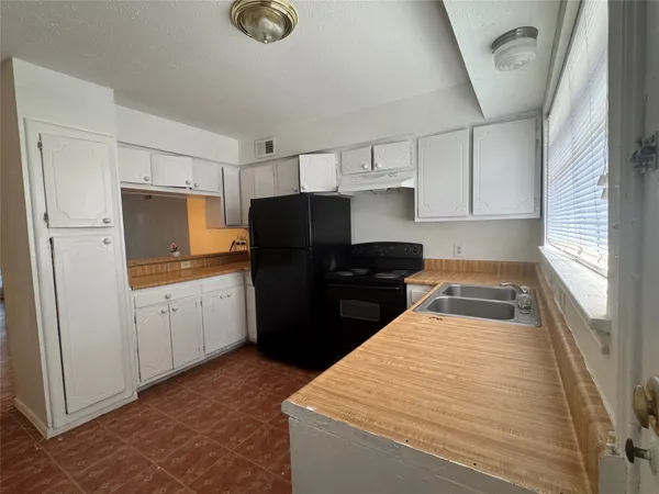 a kitchen with granite countertop white cabinets and refrigerator