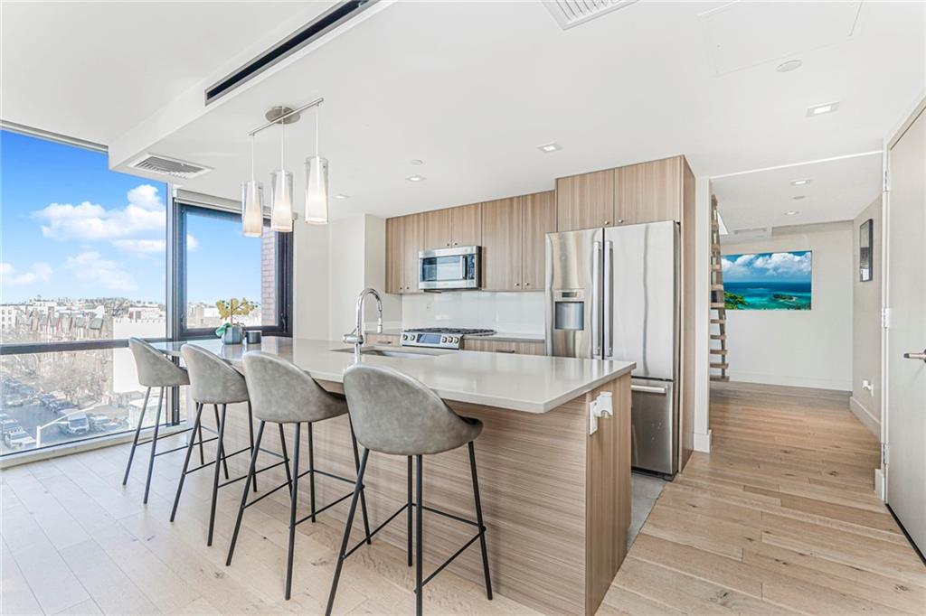 401 95th Street, Unit 6A Brooklyn, NY 11209 - Photo 4 of 24 a kitchen with stainless steel appliances granite countertop a table chairs and a refrigerator