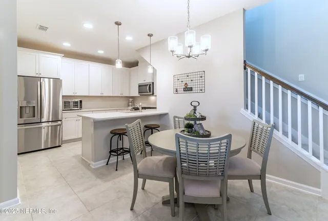 a view of a dining room with furniture a kitchen and chandelier