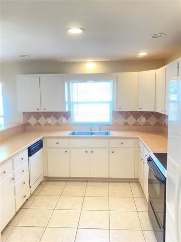 a kitchen with granite countertop white cabinets white appliances with a sink and dishwasher