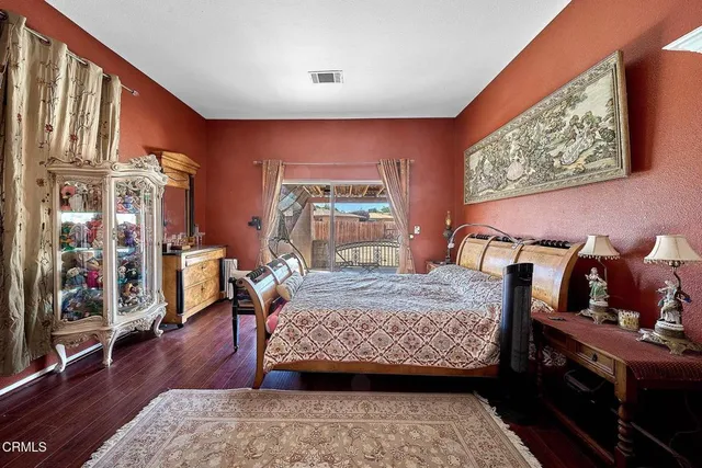 a bedroom with a bed a dresser and wooden floor