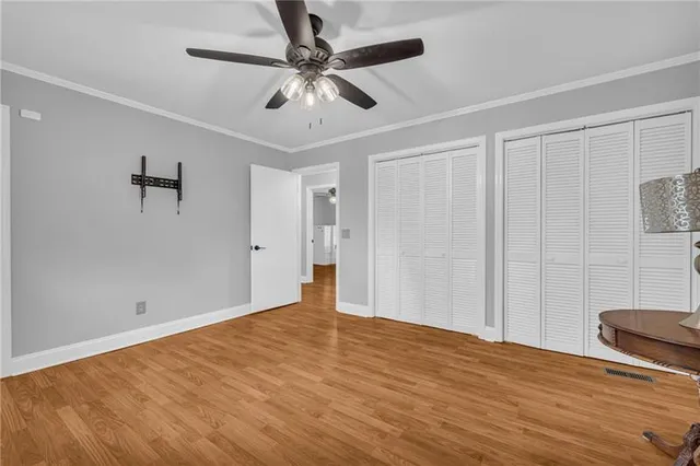 a view of an empty room with wooden floor and a ceiling fan