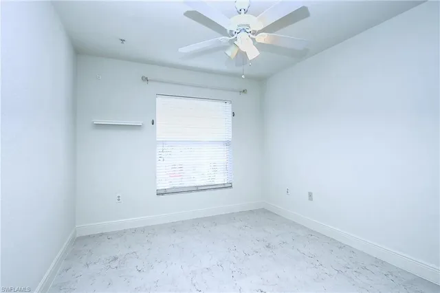 an empty room with a window and ceiling fan
