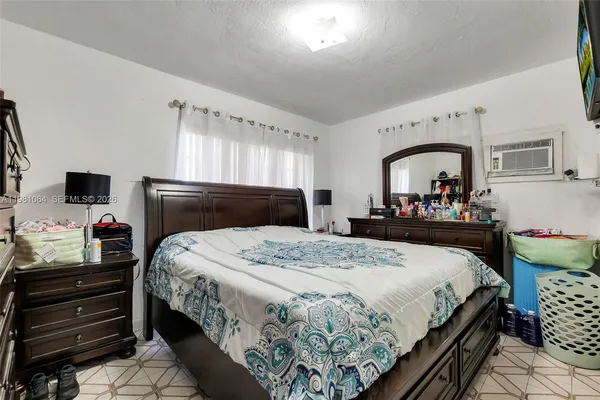 a bedroom with bed and a tv on the dresser