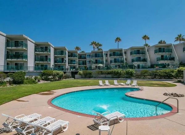 a view of a swimming pool with a lawn chairs under an umbrella